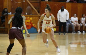 A girl dribbles the basketball while playing in a game.