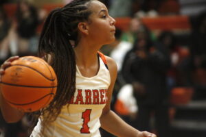 A girl in white shirt holding a basketball.