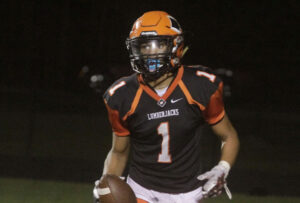 A football player is holding the ball while wearing an orange helmet.