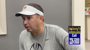 A man wearing an orange visor and gray shirt.
