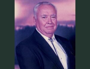 A man in a suit and tie standing next to a wall.