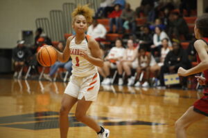 A girl dribbles the basketball on a court.
