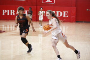 A girl dribbles the basketball while playing against an opponent.