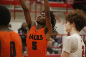 A man in an orange and black uniform is playing basketball.