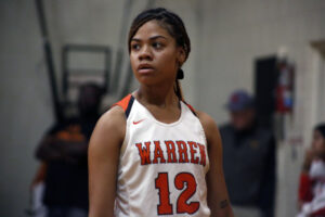 A woman in white and orange basketball uniform.
