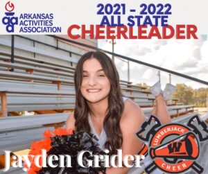 A cheerleader posing for the camera in front of bleachers.