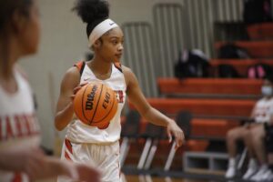 A girl holding onto a basketball in the middle of a court.