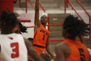 A basketball player is in the air with his arm raised.