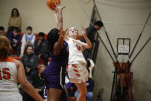A girl is jumping up to hit the basketball