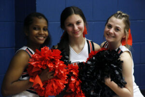 Three young women posing for a picture with pom poms.