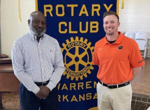 Two men standing in front of a rotary club banner.