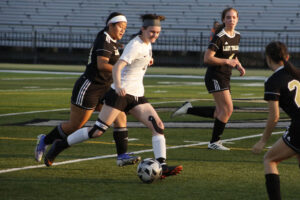 A group of girls playing soccer on the field.