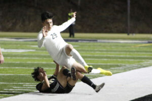 A soccer player is falling over another player.