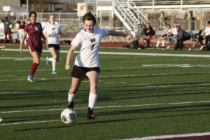 A girl is playing soccer on the field