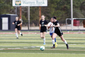 A group of girls playing soccer on the field.