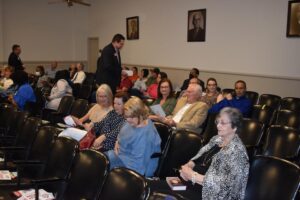 A group of people sitting in chairs at a meeting.