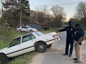 A police officer standing next to a car on the side of a road.