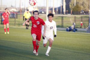 Two young men playing soccer on a field.