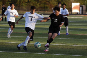 Two men playing soccer on a field with other players.