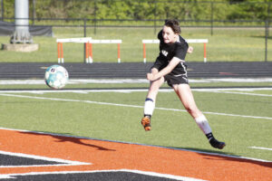 A girl kicking around the soccer ball on a field.