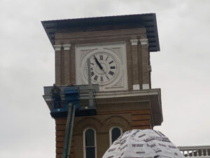 A man on a crane is working on the clock tower.