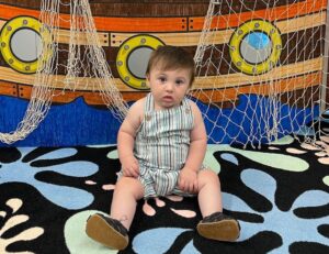 A baby sitting on the floor of an indoor playground.