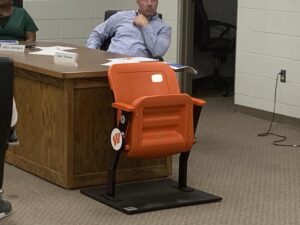 A man sitting at his desk in an orange chair.