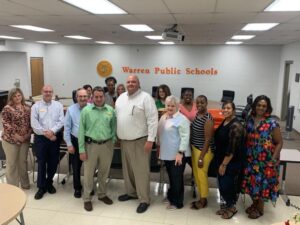A group of people standing in front of a sign.