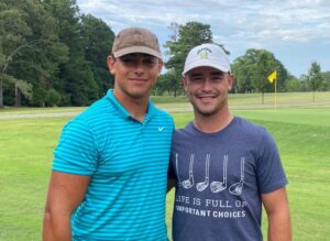 Two men standing next to each other on a golf course.