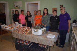 A group of people standing around a table with food.