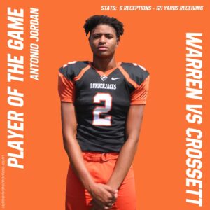A football player is standing in front of an orange background.