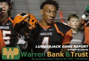 A football player is holding his helmet and looking at the camera.