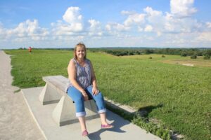 A woman sitting on top of a bench in the middle of a field.