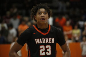 A young man in black and orange shirt playing basketball.