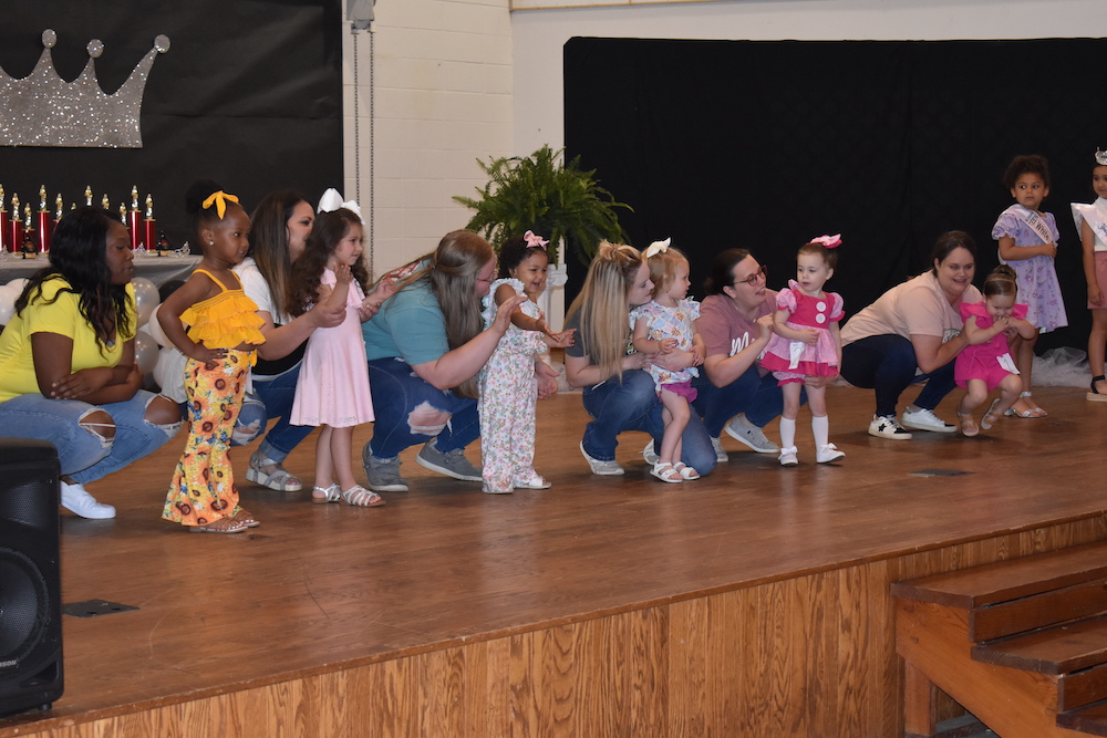 A group of children on stage with one person holding something.