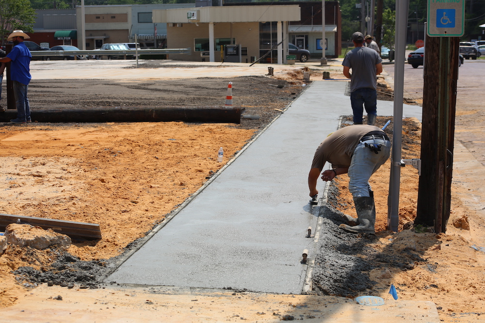 A man is working on the sidewalk of a street.