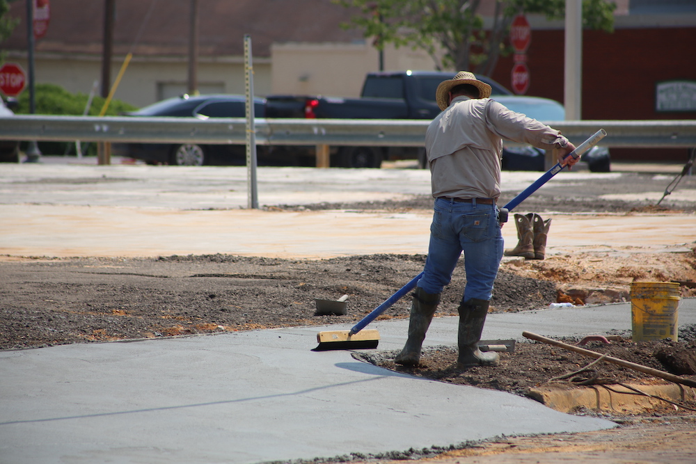 A man is sweeping the sidewalk with a broom.