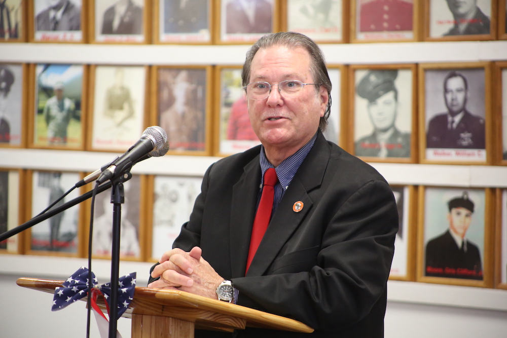 A man in suit and tie standing at a podium.