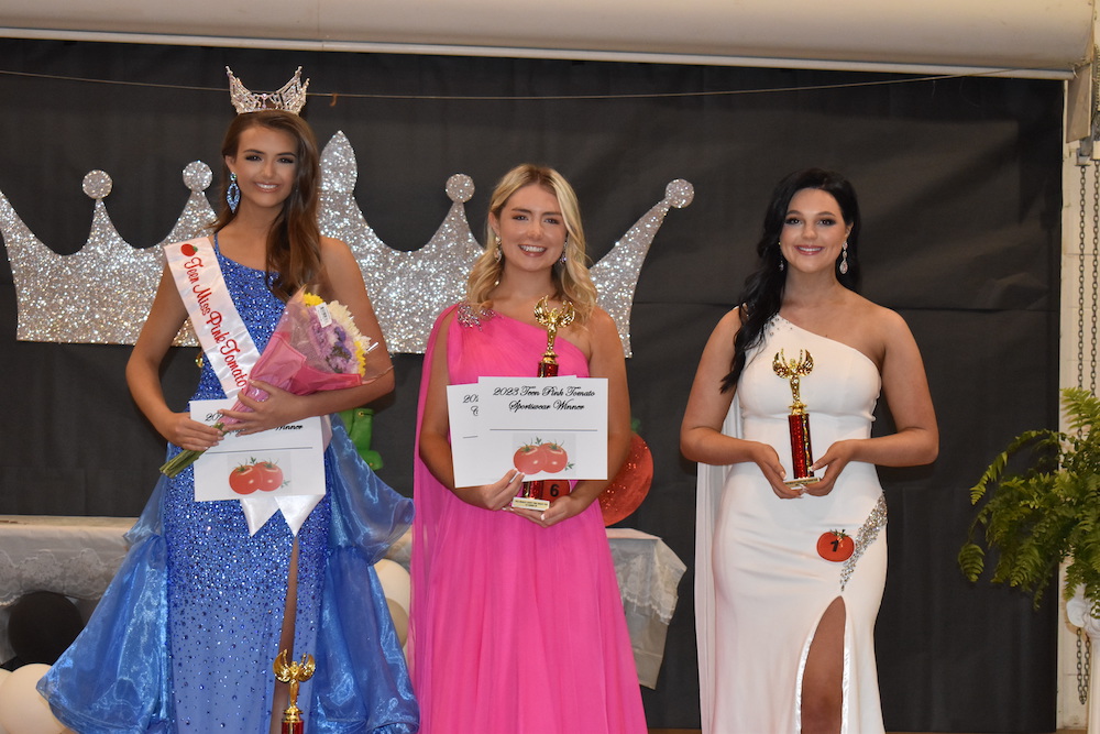 Three women in formal wear holding awards and smiling.