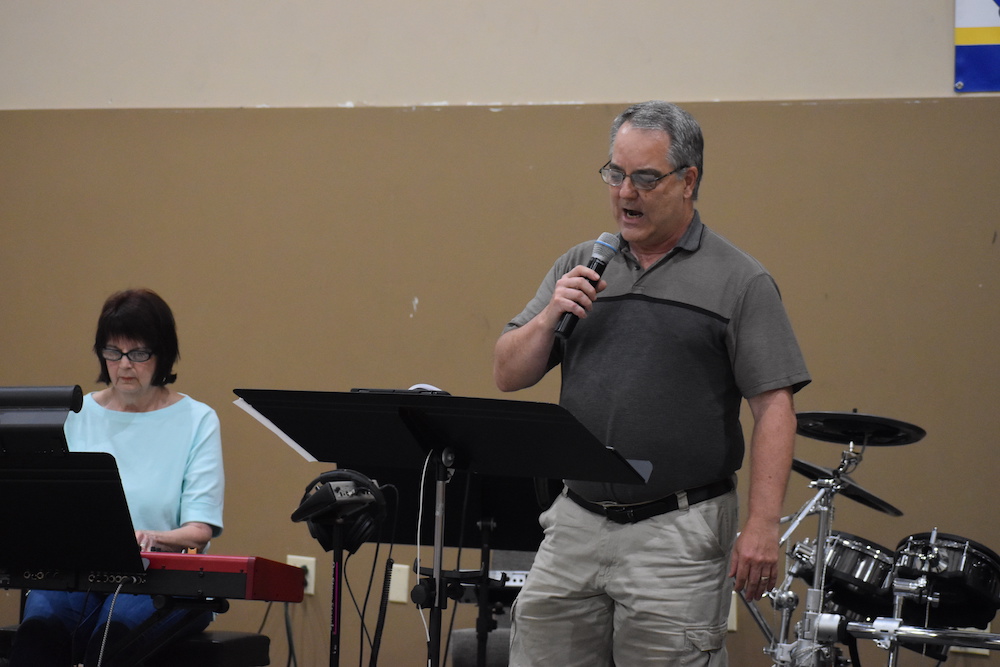 A man is speaking into a microphone at a concert.