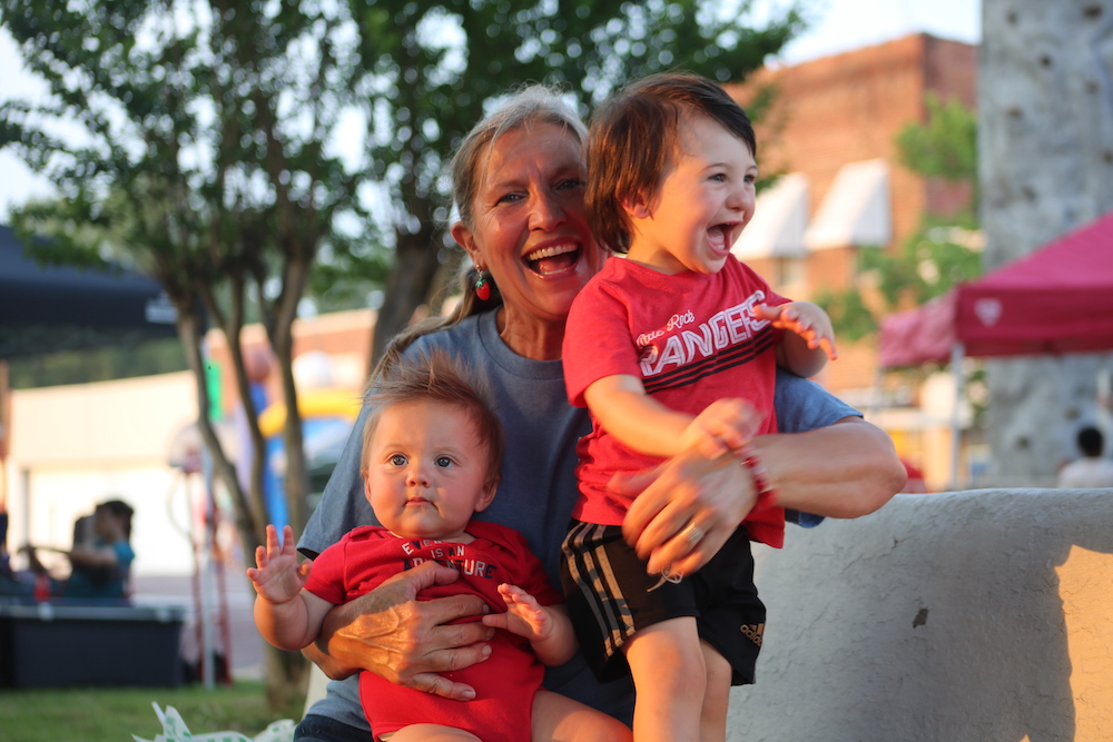 A woman holding two children and smiling for the camera.