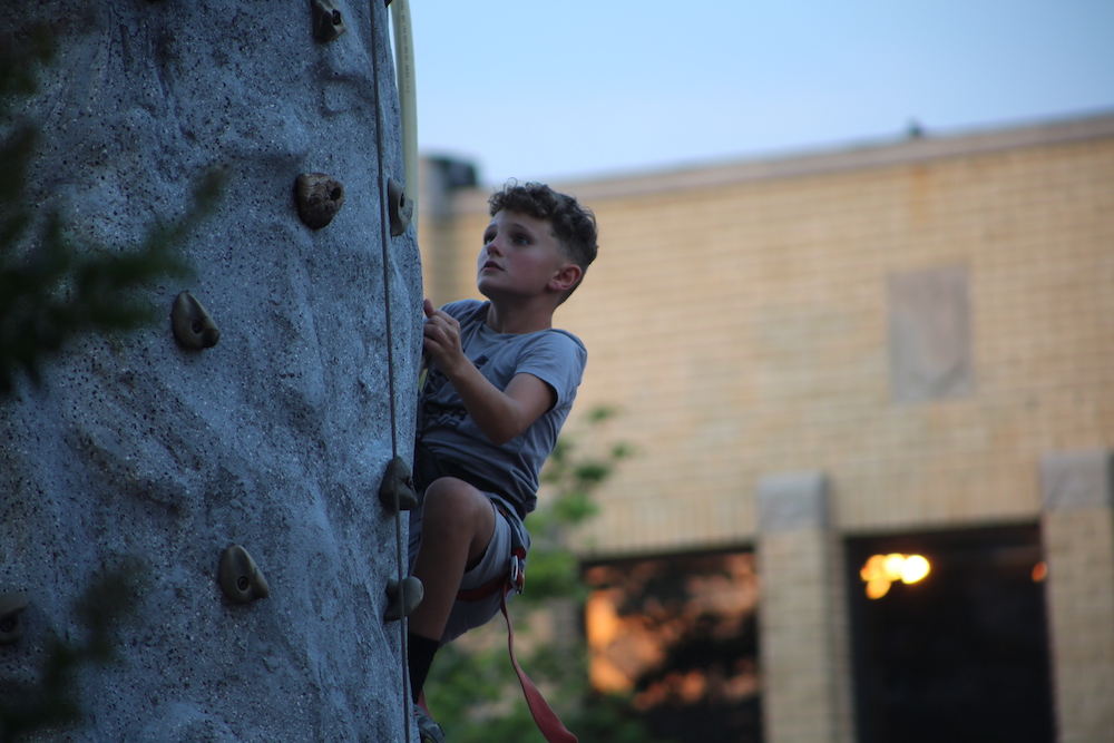 A boy climbing up the side of a rock wall.