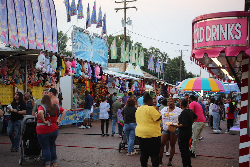 A crowd of people walking around an amusement park.