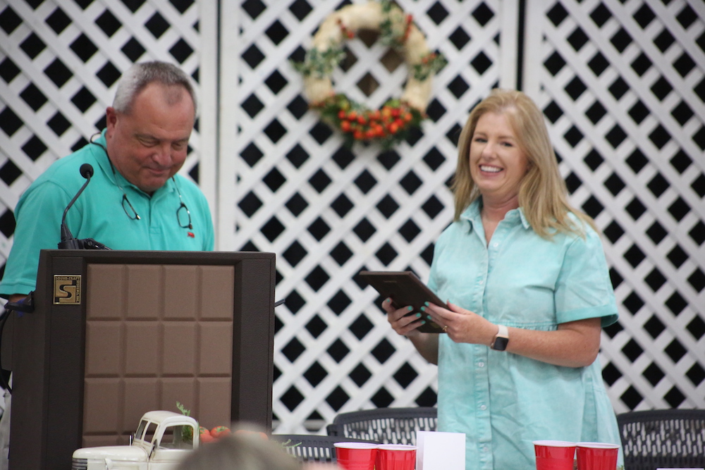 A woman holding an ipad standing next to another man.