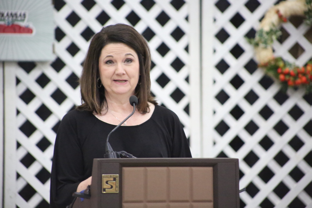 A woman standing at the podium with her hands on the microphone.