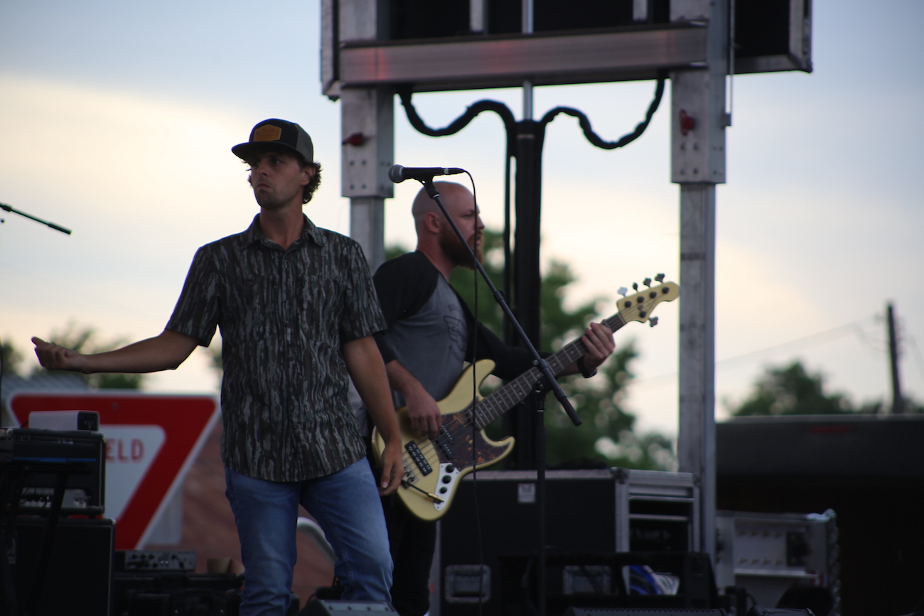 Two men are playing guitar and singing on stage.