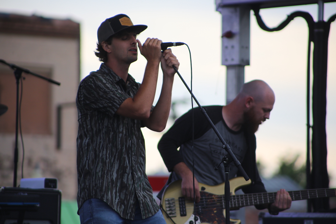 A man holding a microphone while standing next to another man.