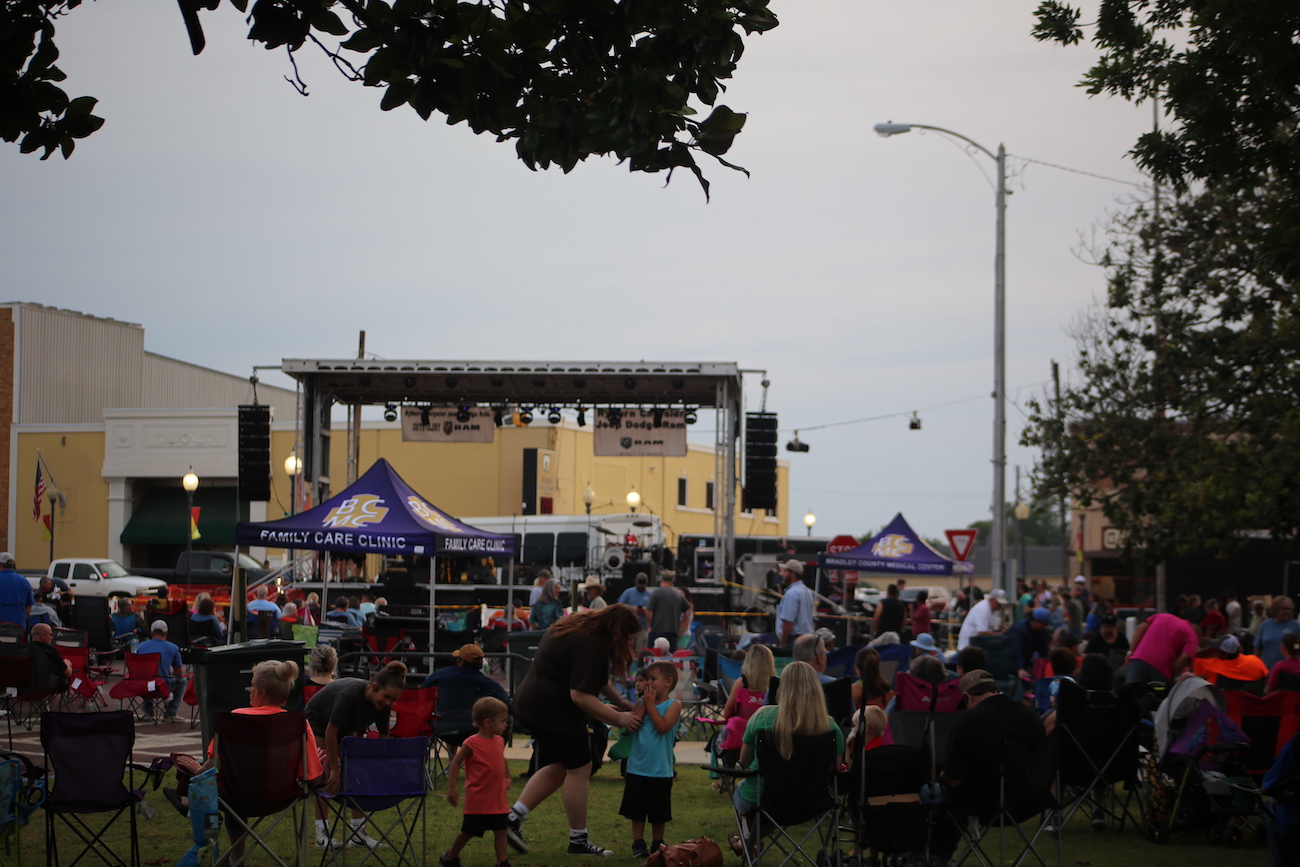 A crowd of people standing around in the grass.
