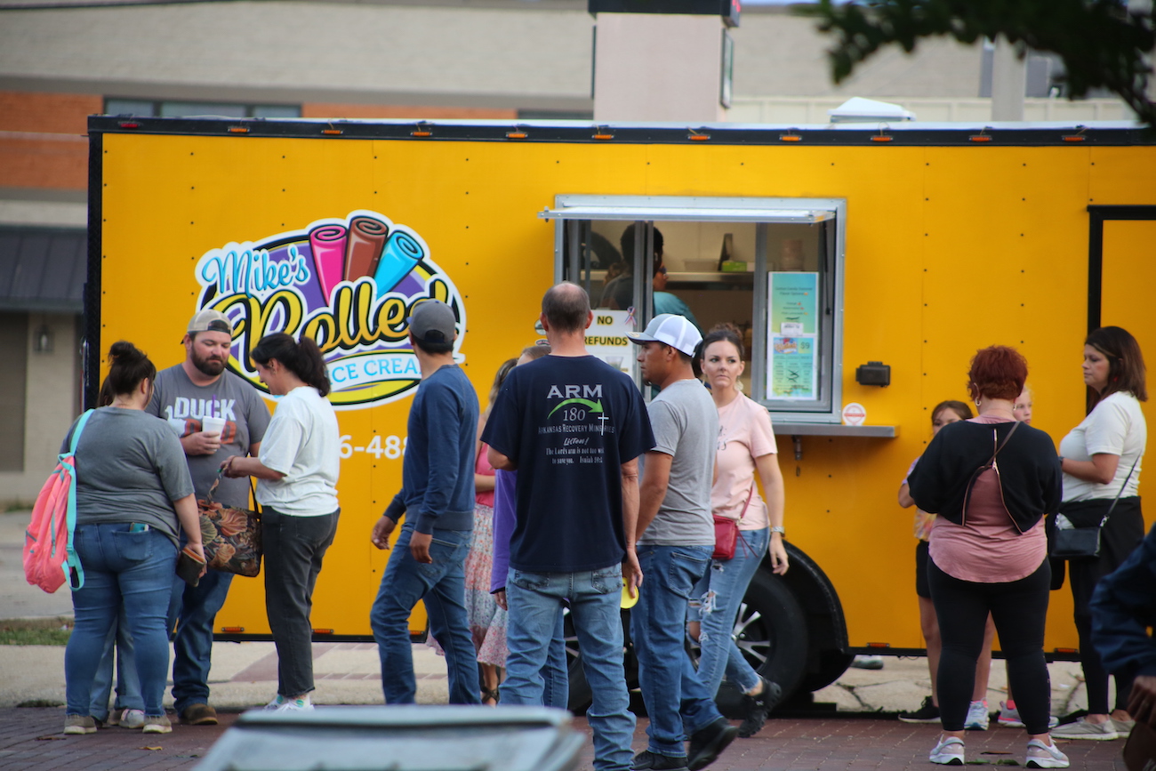 A group of people standing around a food truck.