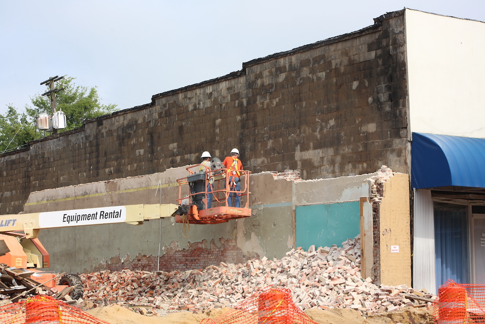Two construction workers are on a platform.